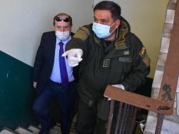 Policías bolivianos custodian al hasta ahora ministro interino de Salud de Bolivia, Marcelo Navajas (i), quien fue arrestado este miércoles en un caso de supuesta corrupción. EFE
