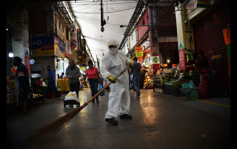 Un trabajador en atuendo protector barre en la Central de Abasto. AFP/R. Arangua