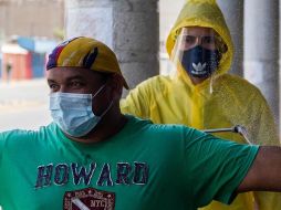 Un trabajador sanitario desinfecta a un grupo de personas antes de entrar a un local comercial, en Maracaibo, Venezuela. EFE/H. Chirinos