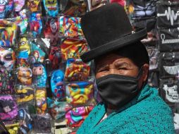 Una mujer aymara camina cerca de un puesto de cubrebocas de tela en La Paz, Bolivia. EFE/M. Alipaz