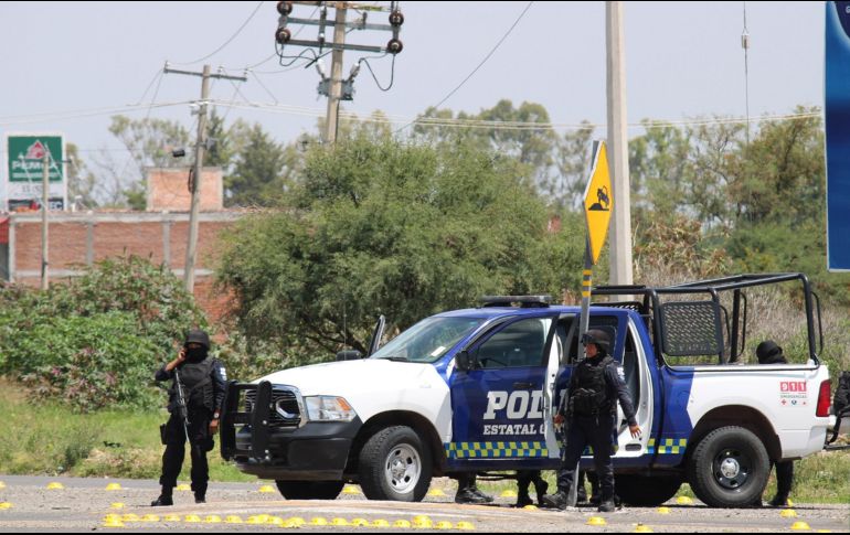Policías estatales vigilan las cercanías del sitio donde sus compañeros fueron ultimados. EFE