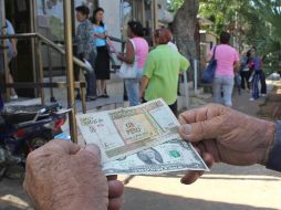 Un hombre muestra un peso convertible cubano y un dólar estadounidense. EFE/ARCHIVO