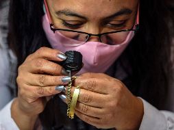 Una trabajadora del Nacional Monte de Piedad hace una valuación de una pieza de joyería de oro. AFP/P. Pardo