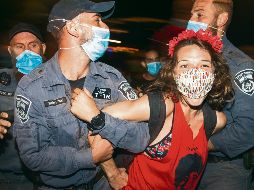 Arresto. Oficiales someten a una manifestante de las protestas afuera de la residencia del premier. AP