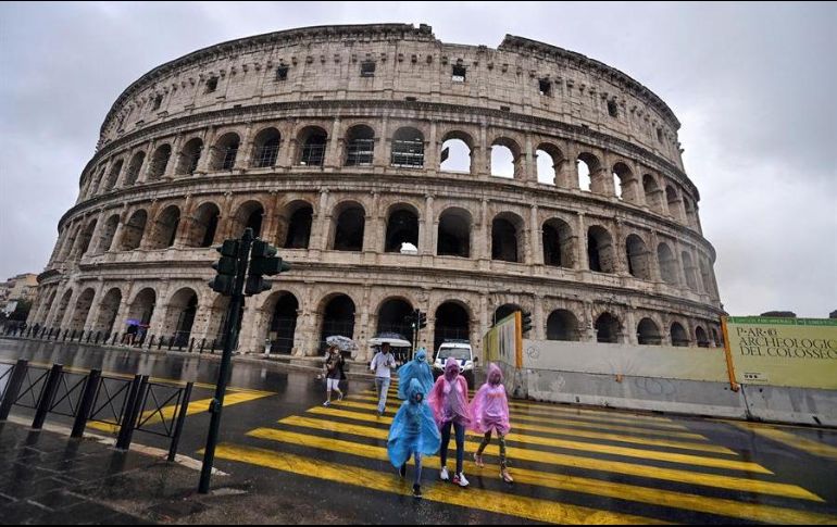 Varias personas caminan cerca del Coliseo romano durante un día lluvioso. El histórico edificio fue reabierto tras permanecer varios meses cerrado por la pandemia. EFE/R. Antimiani