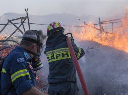 Bomberos rocían agua para apagar el incendio, en Anavissos, una aldea a la orilla del mar en el sur de Attica, en Atenas, Grecia. XINHUA/M. Lolos