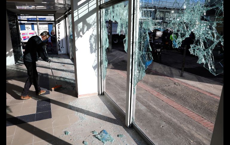 Un hombre limpia hoy los escombros de un local comercial destruido tras los enfrentamientos. EFE/C. Ortega