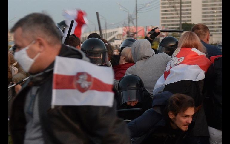 Policías antidisturbios con pasamontañas detuvieron a manifestantes y los llevaron a furgones. EFE