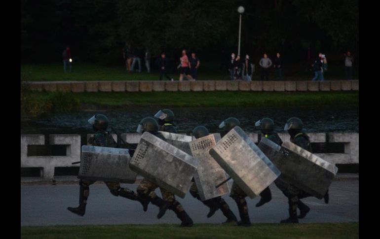 Policías antidisturbios con pasamontañas detuvieron a manifestantes y los llevaron a furgones. EFE