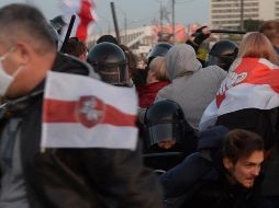 Policías antidisturbios con pasamontañas detuvieron a manifestantes y los llevaron a furgones. EFE