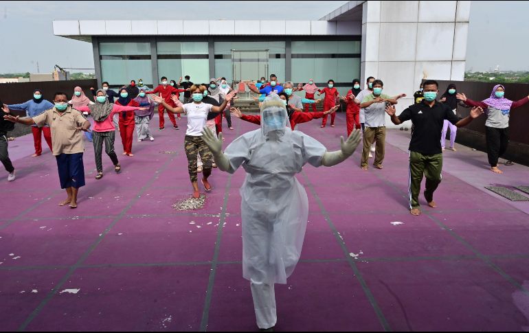 Un instructor de gimnasia dirige hoy a enfermos de COVID-19 en un hotel designado para tratar a pacientes asintomáticos en Karawaci, Indonesia. AFP/A. Berry