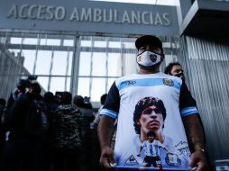 Un hombre muestra un camiseta alusiva al exfutbolista y entrenador argentino Diego Armando Maradona mientras espera a las afueras del hospital. EFE/J. Roncoroni
