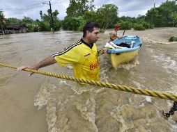Dos personas tratan de cruzar una zona inundada por el desborde de los ríos hoy, en la sierra de Tabasco, otra región afectada por las lluvias. EFE/J. Avalos