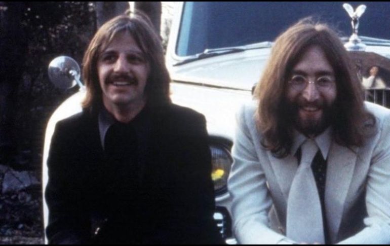 Ringo (izq.) y Lennon (der.) sentados frente a un coche y sonriendo. INSTAGRAM / @ringostarrmusic