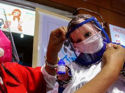 Una mujer viste a una figura de Niño Dios con cubrebocas y careta en una tienda en Ciudad de México. EFE/J. Pazos