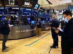 Corredores de bolsa protegidos con cubrebocas trabajan en Wall Street. AP/C. Ziemer