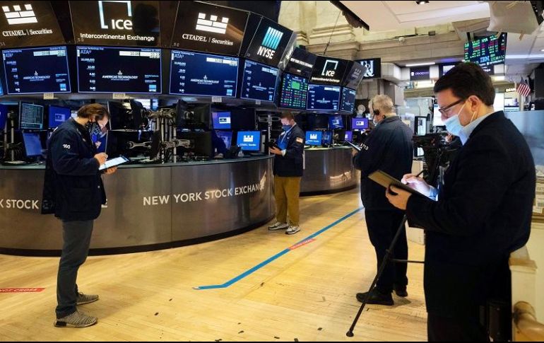 Corredores de bolsa protegidos con cubrebocas trabajan en Wall Street. AP/C. Ziemer