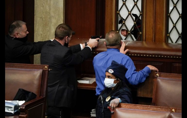 Policías apuntan armas a manifestantes que intentan ingresar a la Cámara de Representantes en el Capitolio. AP/J. Scott Applewhite