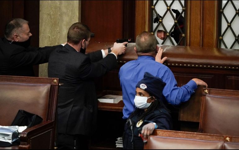 Policías apuntan armas a manifestantes que intentan ingresar a la Cámara de Representantes. AP/J. Scott Applewhite