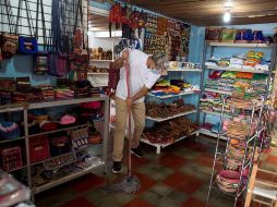 Un trabajador limpia un establecimiento de ventas de artesanías en el municipio de Valle de Ángeles, Honduras. EFE/G. Amador