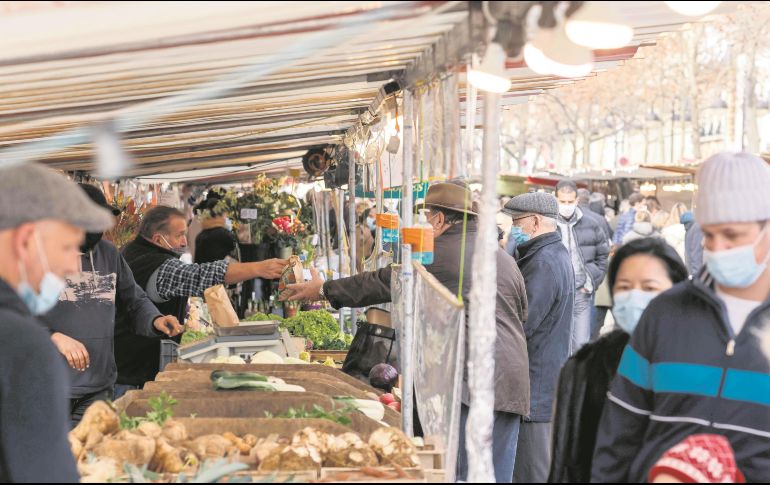 Botellas de gel y cubrebocas se observan entre los puestos de un tianguis parisino, pero no el control de la distancia. AFP