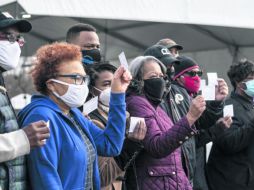 CAMPAÑA. Residentes de Maryland muestran sus tarjetones de vacunación en el estacionamiento de un parque de diversiones. AFP