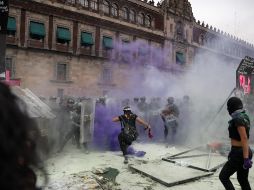 Policías repelen a encapuchadas que intentan cruzar por donde las vallas fueron derribadas. AP/R. Blackwell