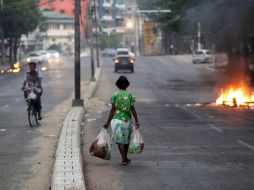 Personas se desplazan por una calle junto a hogueras que simbolizan la resistencia contra el golpe de Estado este miércoles en Rangún, Birmania. EFE