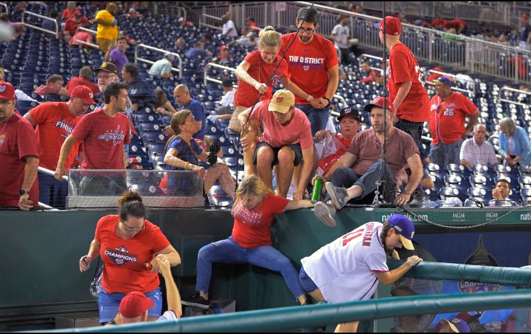 Algunos aficionados saltaron a la cancha en busca de protegerse. AP