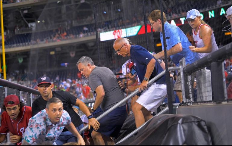Algunos aficionados saltaron a la cancha en busca de protegerse. AP