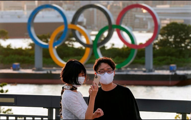 Japoneses se toman una fotografía frente el Monumento de los anillos olímpicos en Odaiba. EFE / K. Mayama