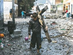TRAGEDIA. Con una cruz a cuestas un vecino de Paulina ayuda a buscar pertenencias que ve flotando entre los escombros en la Calles Costa Chica. G.GALLO
