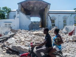 Personas pasan junto a los restos de un templo en Les Cayes, Haití, un día después de sismo de 7.2. AFP/R. Loussaint