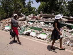 Dos mujeres caminan junto a una vivienda derrumbada durante el terremoto del pasado 14 de agosto, hoy, en Marceline, Haití. EFE/O. Barría