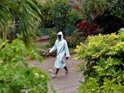 Un hombre camina bajo la lluvia protegido con una capa impermeable en La Habana. EFE/E. Mastrascusa