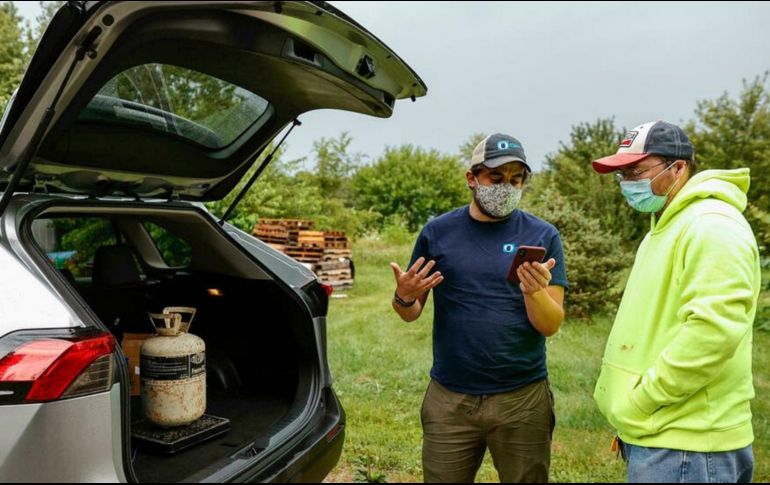 Chad Dorger (izq), del Programa Ambiental en Tradewater, recoge los tanques de refrigerante vacíos de Rick Karas. AFP