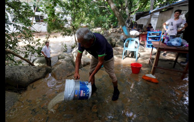 Personas sacan hoy agua de casas inundadas tras las lluvias de 