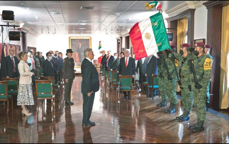 A LA MITAD DEL CAMINO. López Obrador sostiene una bandera nacional antes de rendir su Tercer Informe anual del gobierno en Palacio Nacional. AFP