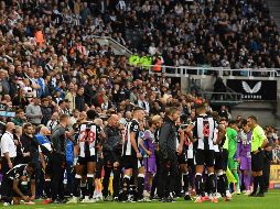 Jugadores se reunieron en las bancas mientras los médicos realizaron su labor. AFP/P. ELLIS