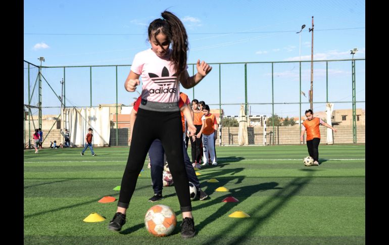 Usando petos coloridos, las niñas hacen ejercicios de estiramiento en el césped antes de que Yusef Chaba sople el silbato para comenzar la práctica. AFP/Z. Al Obeidi