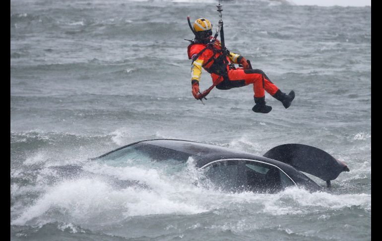 Un guardacosta colgado de un cable de un helicóptero se posicionó encima del vehículo, en medio de una ventisca. AP/J. Barnes