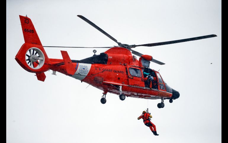 Un guardacosta colgado de un cable de un helicóptero se posicionó encima del vehículo, en medio de una ventisca. AP/J. Barnes