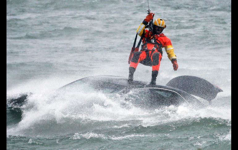 Un guardacosta colgado de un cable de un helicóptero se posicionó encima del vehículo, en medio de una ventisca. AP/J. Barnes