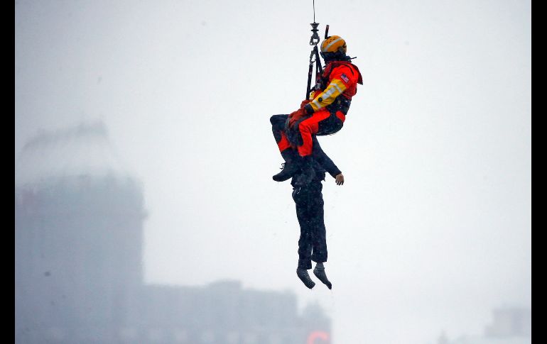Un guardacosta colgado de un cable de un helicóptero se posicionó encima del vehículo, en medio de una ventisca. AP/J. Barnes