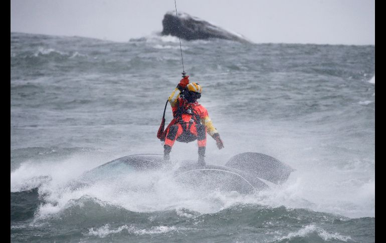 Un guardacosta colgado de un cable de un helicóptero se posicionó encima del vehículo, en medio de una ventisca. AP/J. Barnes