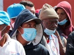 Migrantes con cubrebocas hacen fila para recibir sus alimentos en el albergue la Casa del Peregrino, en la Basílica de Guadalupe. EFE/J. Méndez