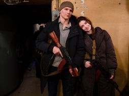 Una pareja de jóvenes se une a la defensa de Kiev y posan para la cámara con una sonrisa luego de recibir sus armas. EFE / M. Palinchak
