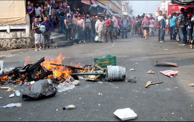 Los migrantes comenzaron el fuego al prender una silla de madera, así como artículos de plástico y rejas de madera al tiempo que exigían a los comerciantes y personas que se encontraban comprando continuar su camino.EFE / J. Blanco