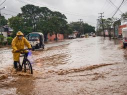 Personas transitan por una avenida inundada en el municipio de Tehuantepec, Oaxaca. EFE/L. Villalobos