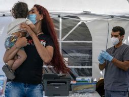 Una mujer calma a su hijo previo a la toma de muestras para detectar el COVID, en Tijuana. AFP/G. Arias